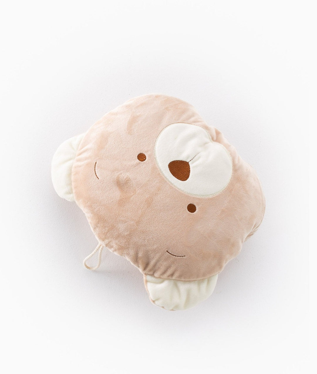 Top down view of beige bear head travel pillow with embroidered features