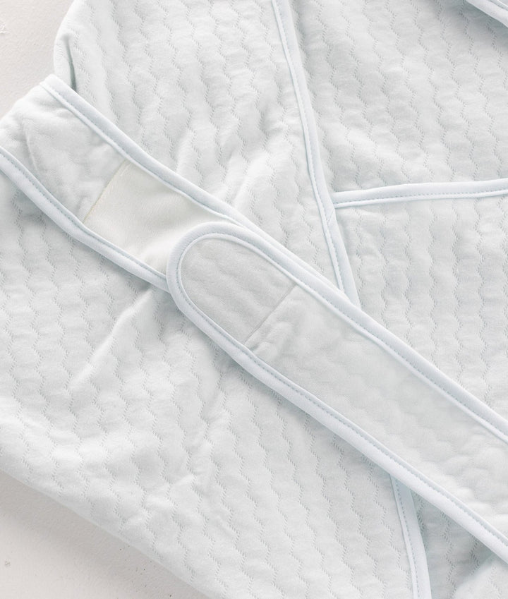 Close-up of light blue swaddle waffle texture, edge piping, and velcro fastening mechanism