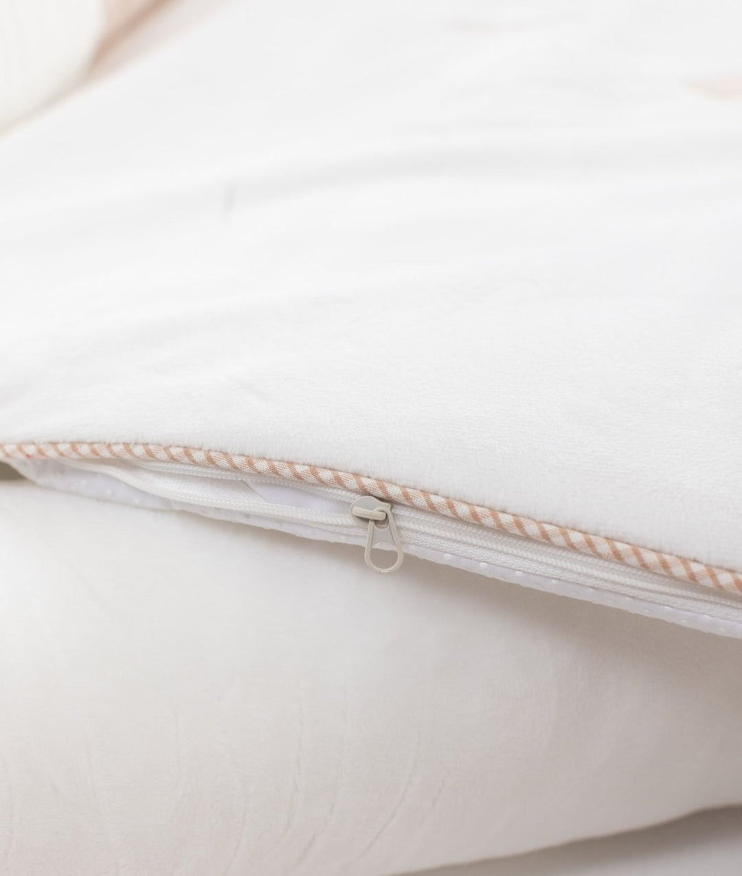 Close-up of white plush outer shell zipper track with striped piping trim