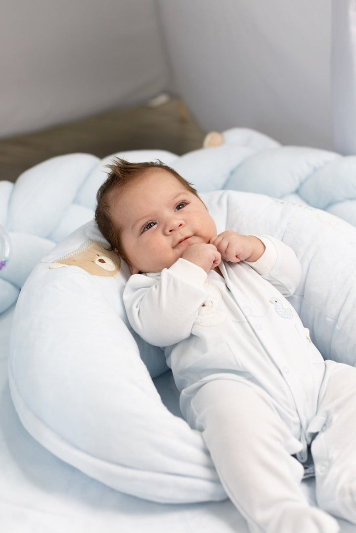 infant resting in light blue nursing lounger supportive curve bear applique