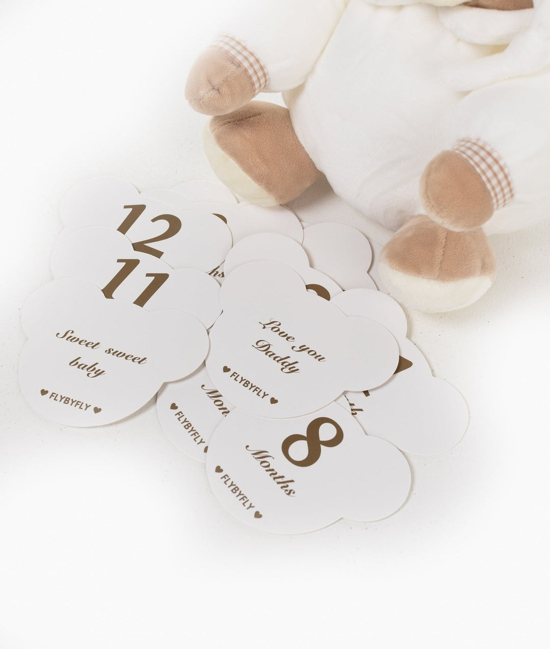 Scattered set of white cloud milestone cards with brown text next to beige bear