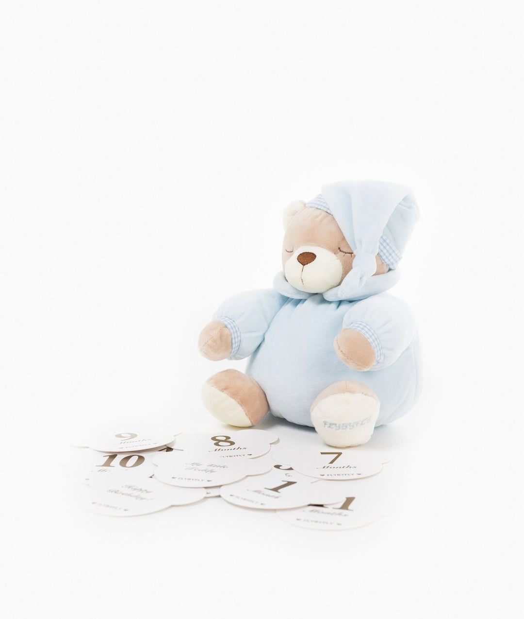 Sleeping blue teddy bear behind fanned stack of numbered baby milestone cards