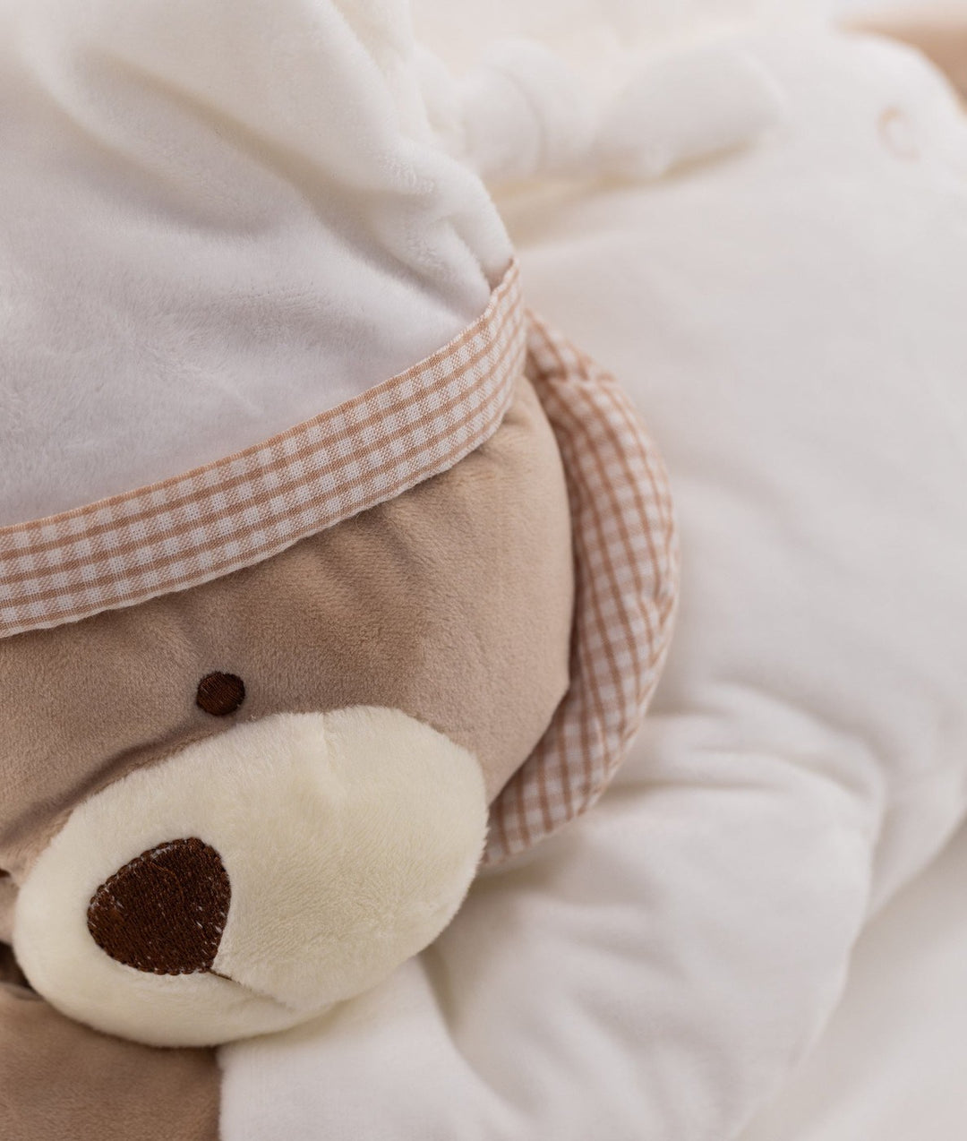 Brown plush bear face detail with dark nose and gingham ribbon band on hat