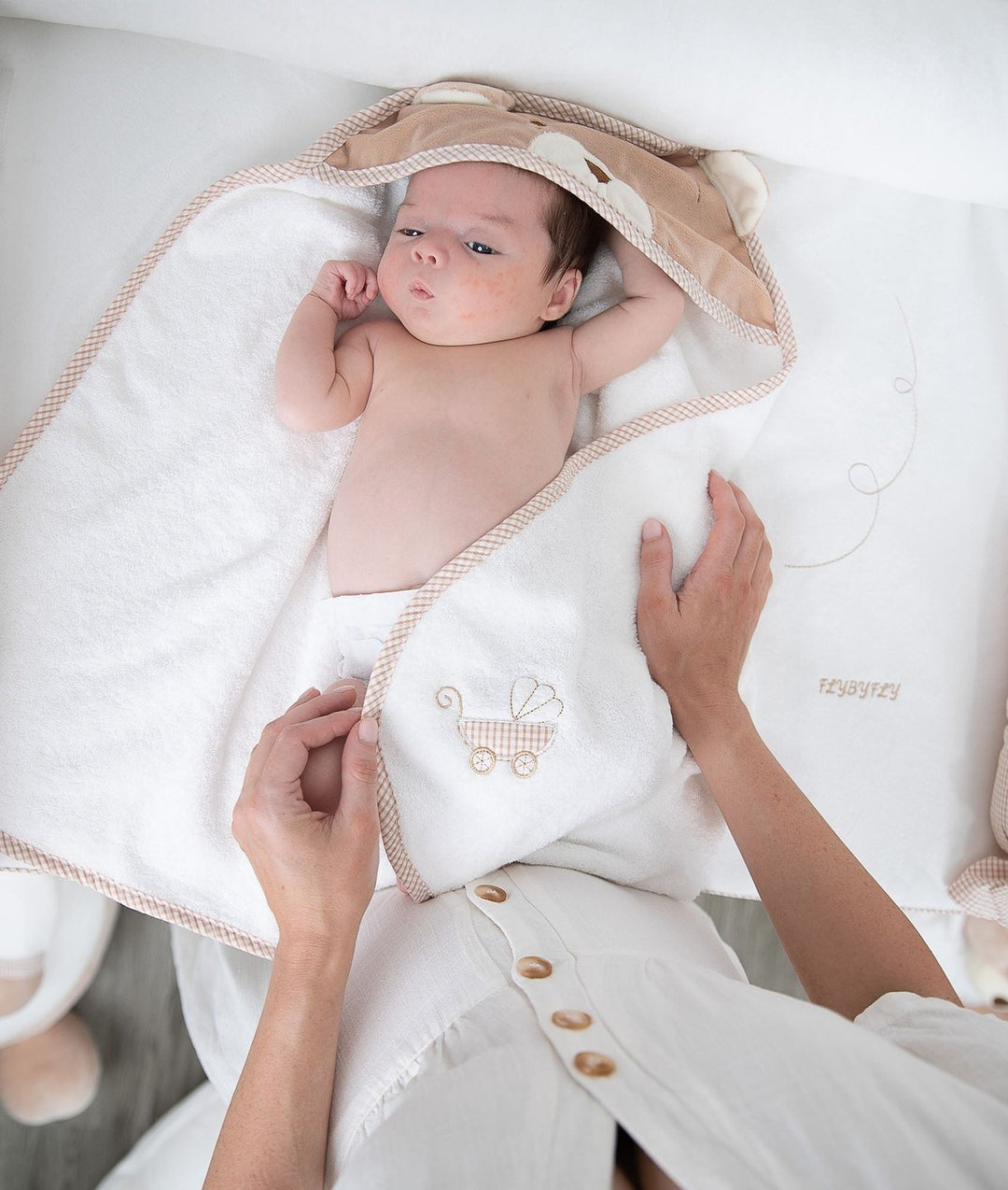 Newborn wrapped in soft beige hooded towel during bath time use case