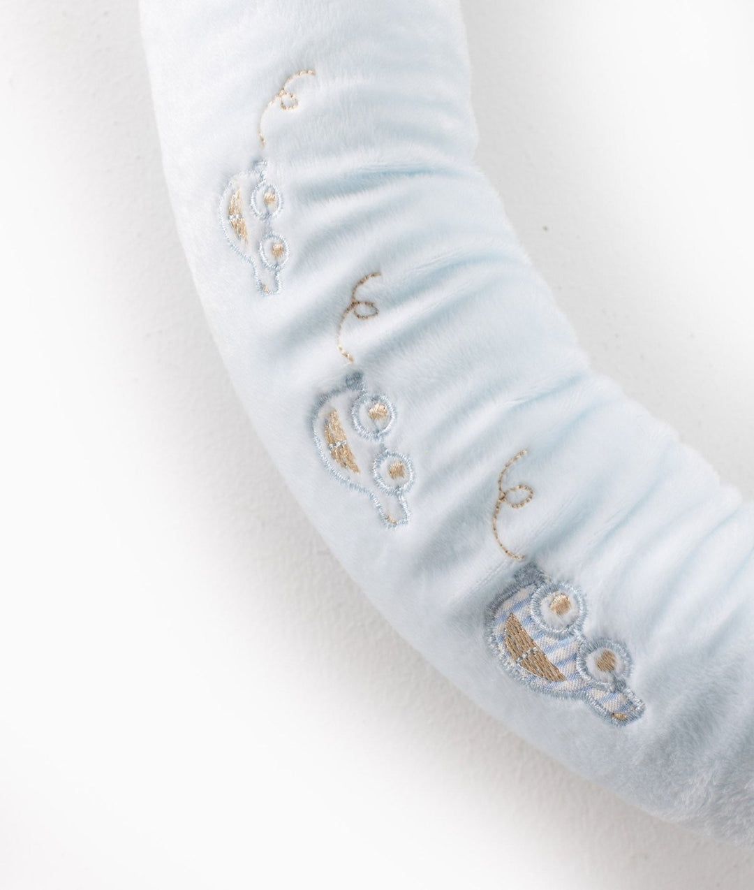 Macro texture of light blue plush fabric with gold and blue embroidered owl details