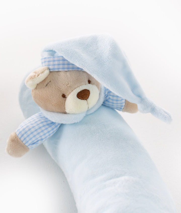 Close-up of brown teddy bear head on blue bolster with gingham nightcap trim