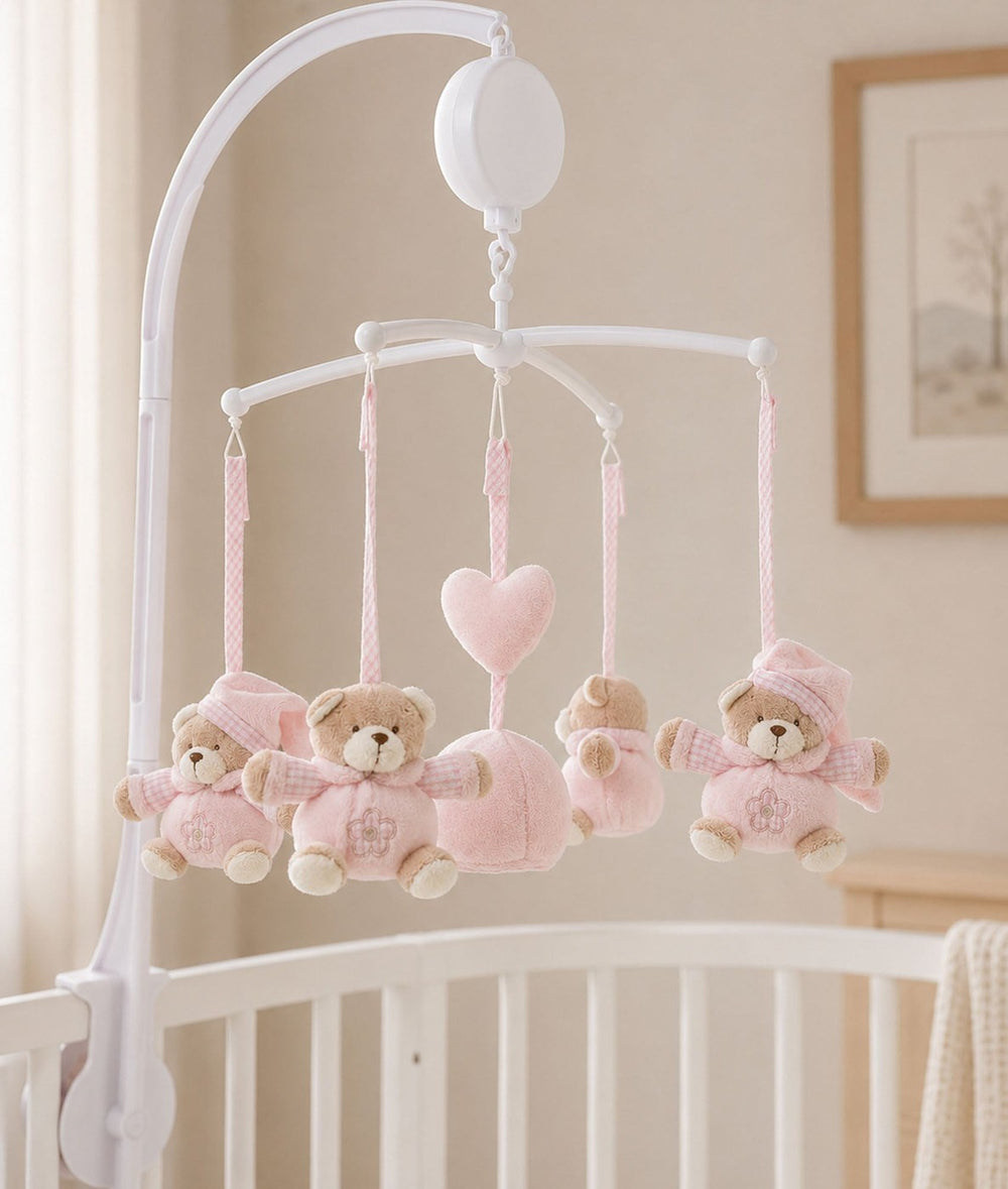pink bear musical mobile attached to white nursery crib rail