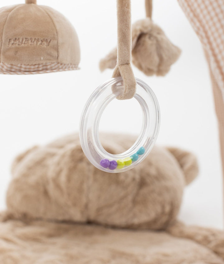 Close-up of clear plastic teether ring filled with colorful beads hanging from beige gym strap