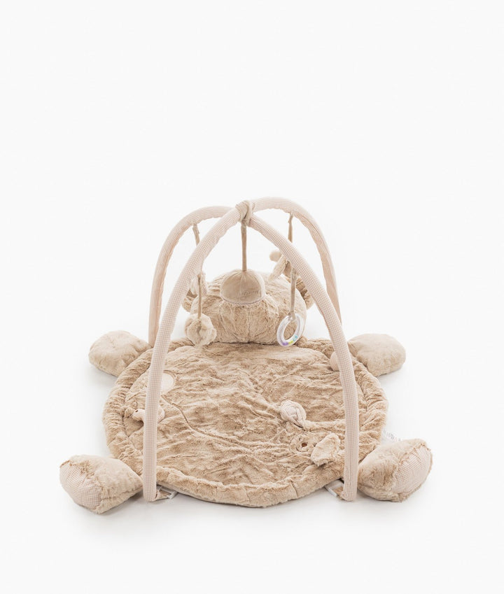 Front view of beige baby gym with dual wicker-style arches holding dangling rattle rings and plush shapes