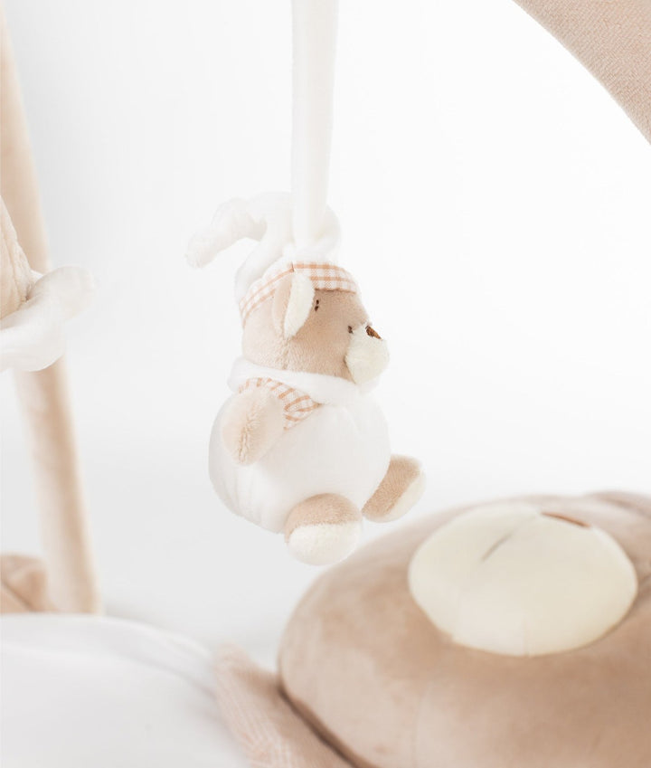 Side view of hanging bear doll toy above plush bear head pillow with cream muzzle