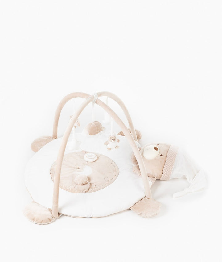 High-angle shot of baby gym arch with suspended toys over cozy beige and white mat