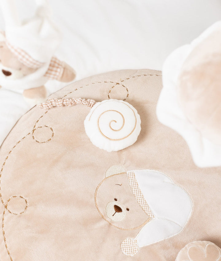 Macro detail of embroidered sleeping bear face and snail toy on beige playmat panel
