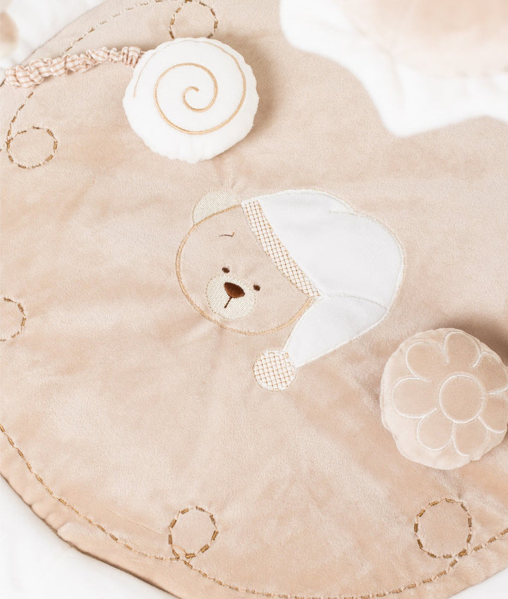 Macro view of embroidered bear design, snail toy, and gold stitching on soft playmat