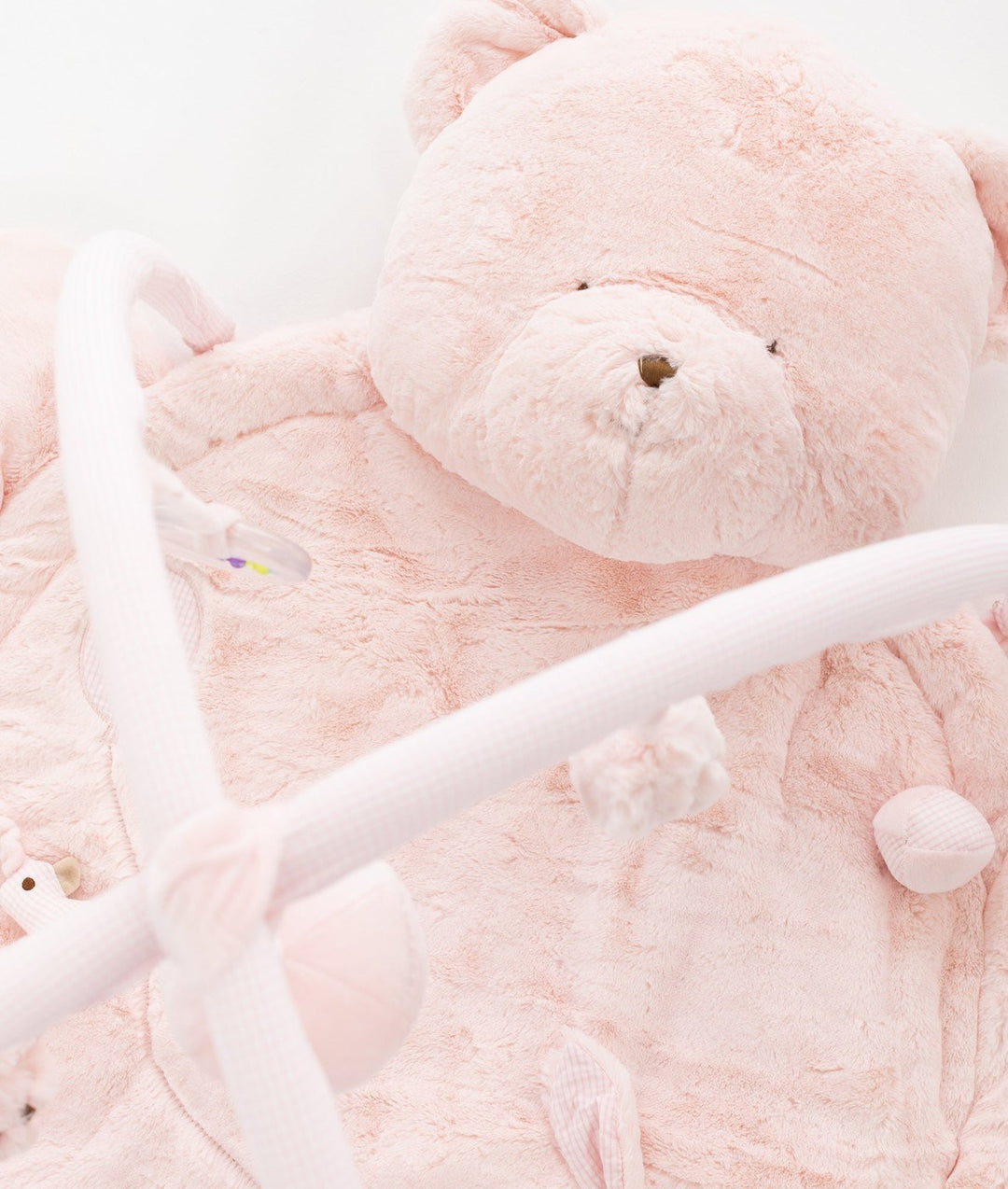Plush pink teddy bear head pillow headrest on playmat with fuzzy material and stitched details