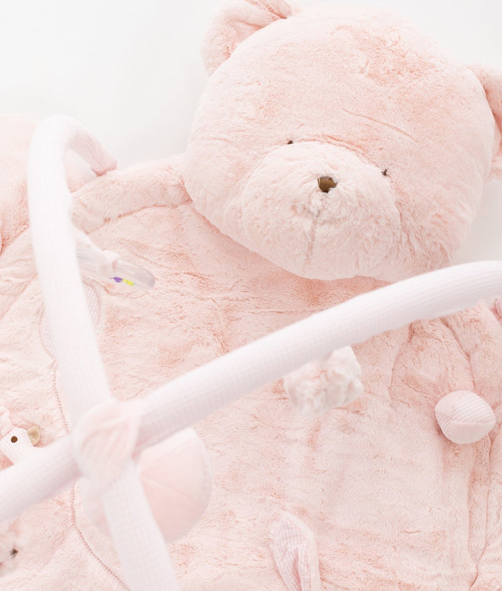 Plush pink teddy bear head pillow headrest on playmat with fuzzy material and stitched details
