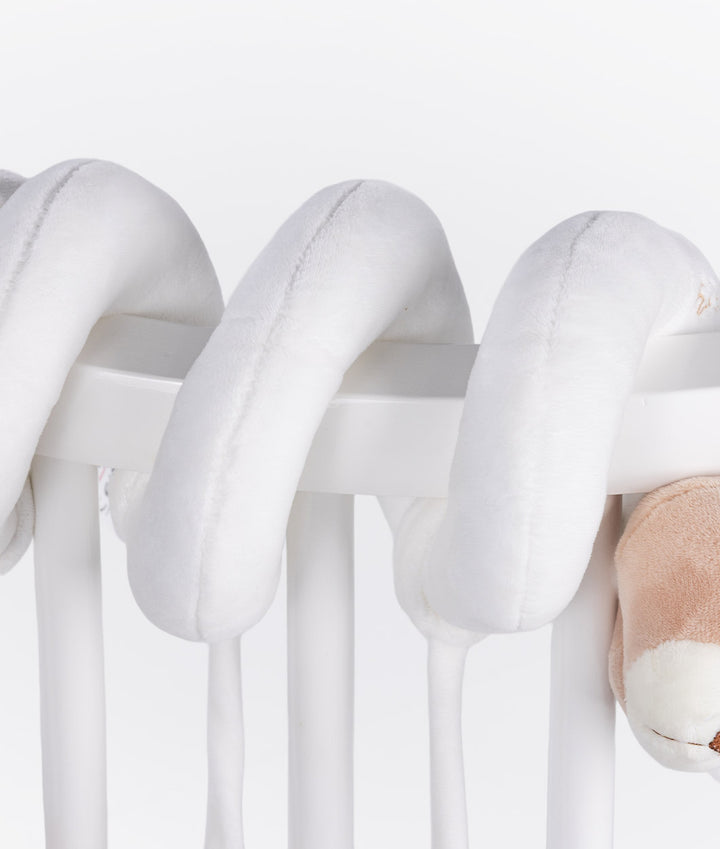 White spiral activity toy looped on cot rail showing tubular fabric texture