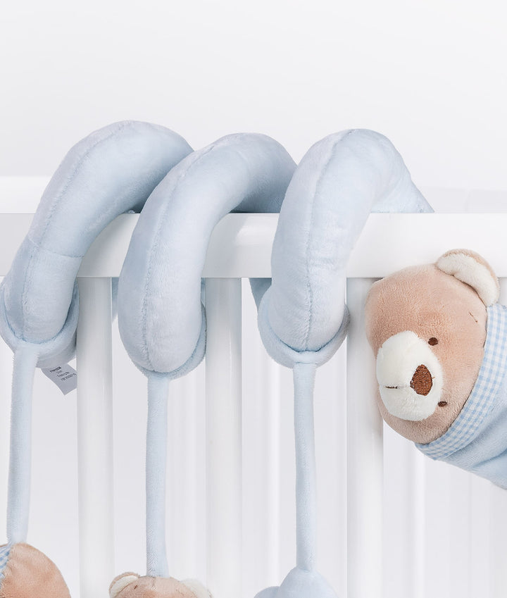Light blue bear spiral activity toy draped over white cot rails with gingham bonnet