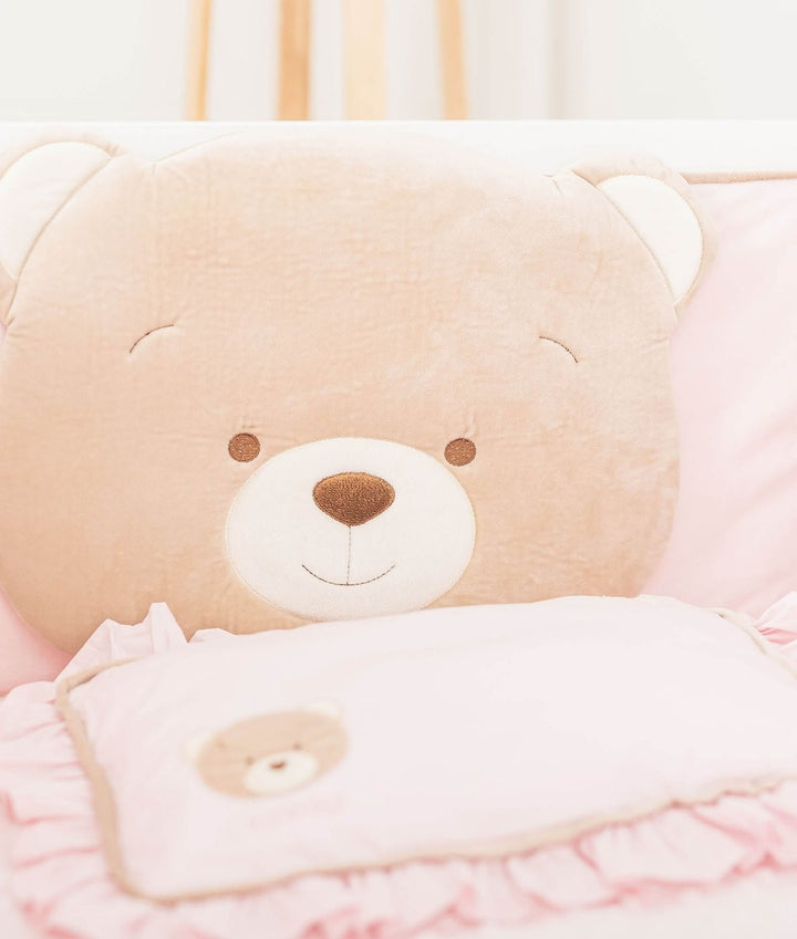 Soft velvety tan bear head cushion detail behind pink ruffled pillow with bear applique