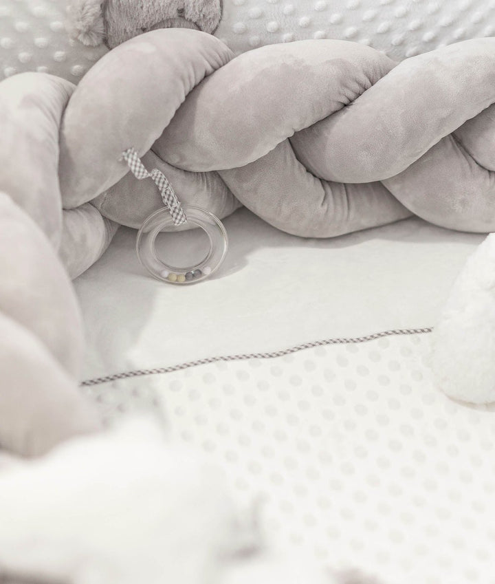 grey velvet braided crib bumper with clear teether ring attached by ribbon