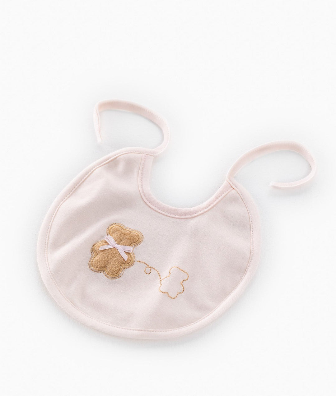 Front view of pink baby bib with long ties, tan teddy bear patch, and gold embroidered cloud design