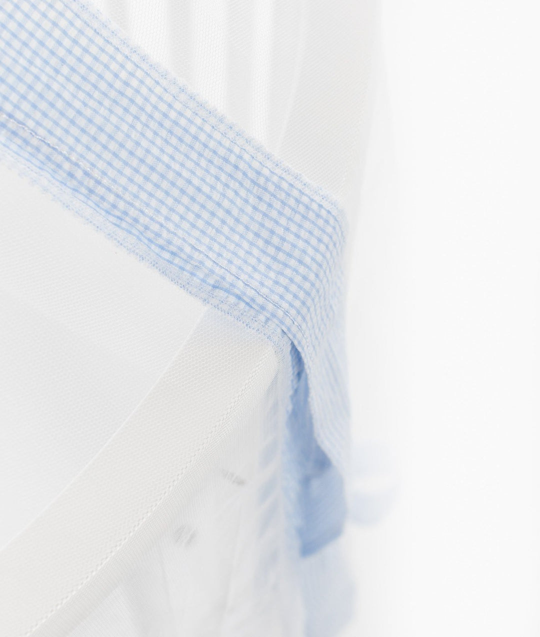 Close-up of light blue and white gingham fabric trim stitched onto the edge of sheer white canopy material