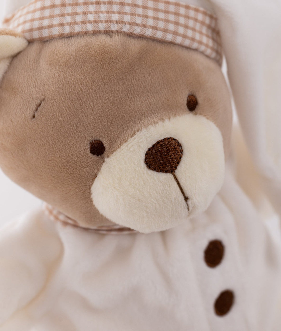 Cuddle Bear face macro shot with embroidered eyes, cream muzzle, and gingham nightcap band