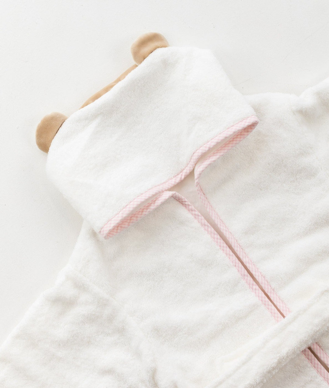 Detail of white 100% cotton hooded bathrobe with tan bear ears and pink trim