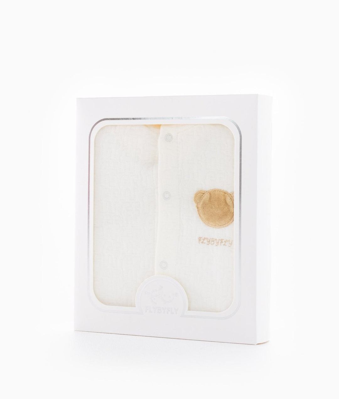 Cream hooded baby jumpsuit in white retail packaging with clear window revealing tan bear patch and FLYBYFLY logo seal