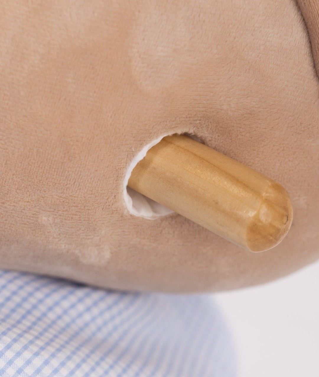 Smooth cylindrical wooden handle on beige plush head of rocking animal toy
